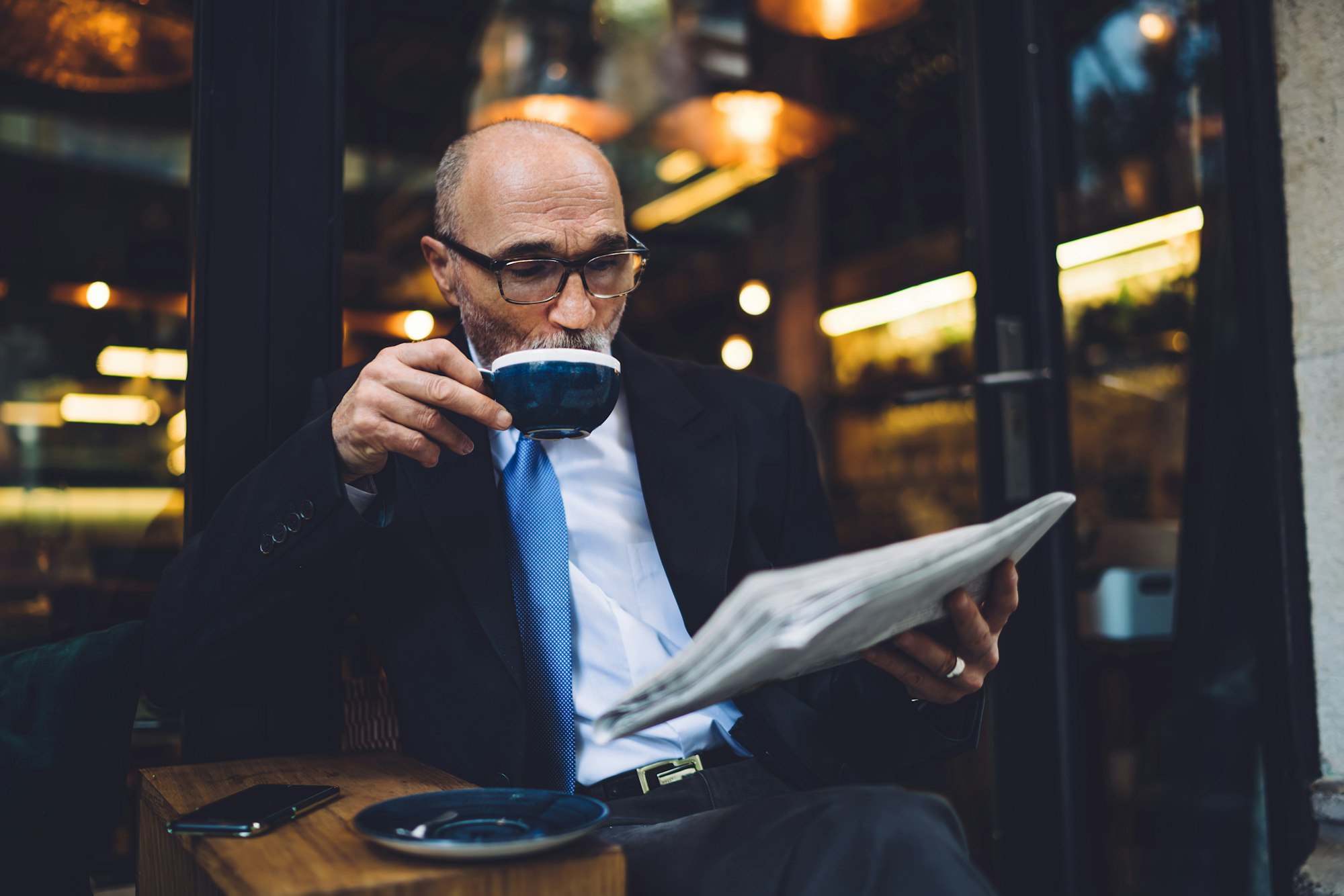 Senior businessman drinking coffee and reading newspaper